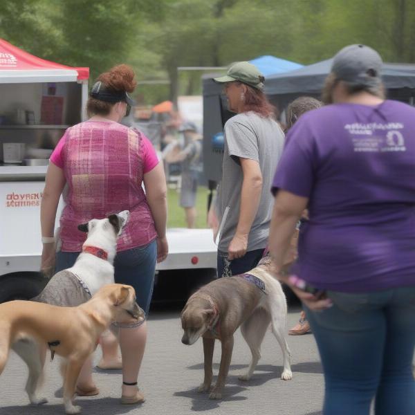 A rescue dogs food truck parked at an adoption event, with people interacting with adoptable dogs.